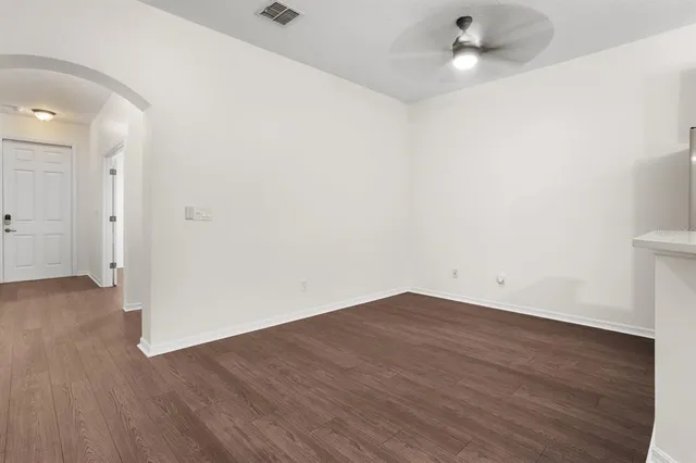 an empty room with wooden floor and ceiling fan