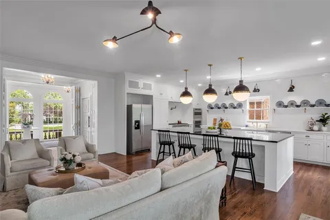 a living room with furniture kitchen view and a wooden floor