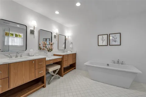 a bathroom with a double vanity sink mirror and bathtub