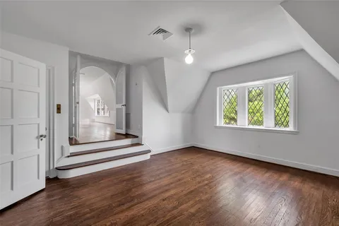 an empty room with wooden floor mirror and windows