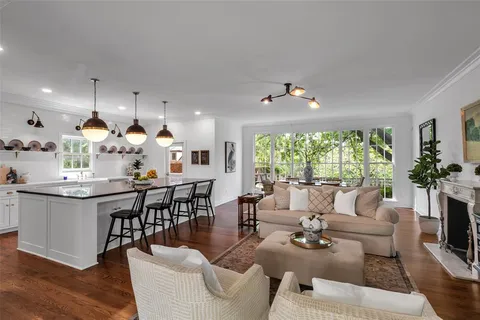 a living room with furniture kitchen view and a large window