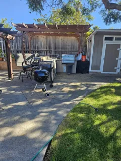 a backyard of a house with barbeque oven table and chairs