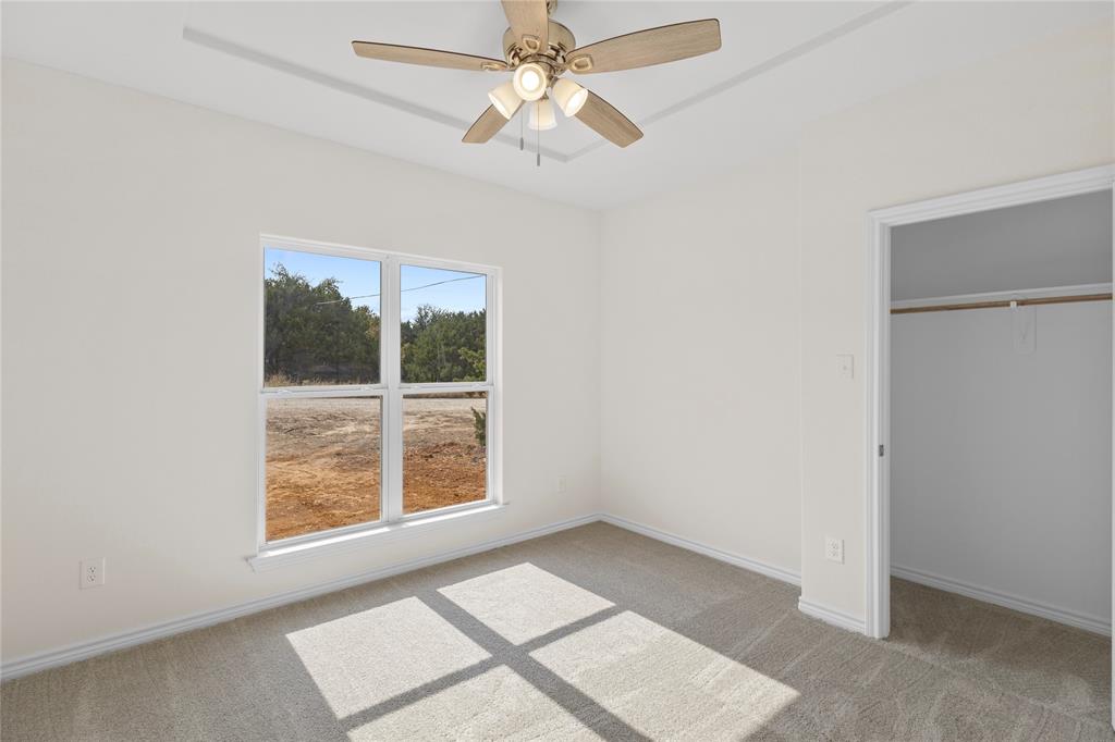 123 Cedar Shadow Lane Whitney, TX 76692 - Photo 19 of 27 an empty room with chandelier fan and windows