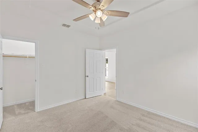an empty room with a chandelier fan and closet area