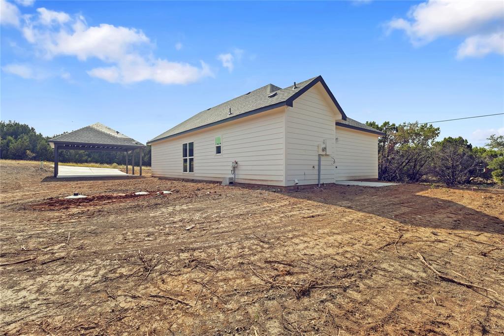 123 Cedar Shadow Lane Whitney, TX 76692 - Photo 25 of 27 a backyard of a house with large trees and a barn