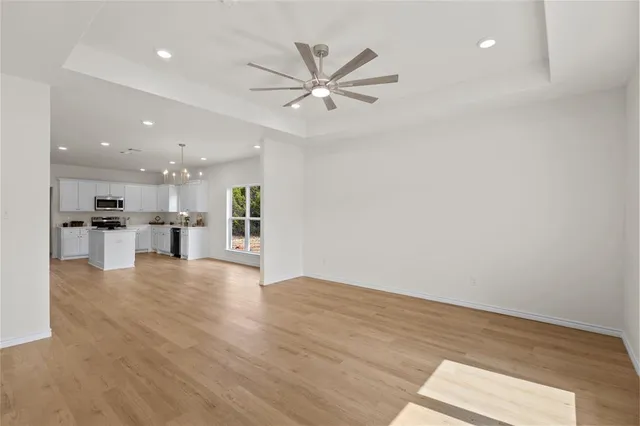 a view of an empty room with wooden floor and a ceiling fan