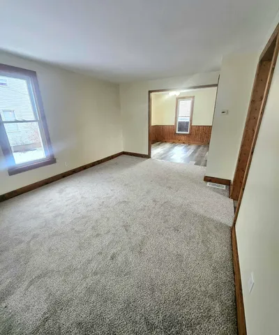 a view of a hallway to a bedroom with wooden floor and windows