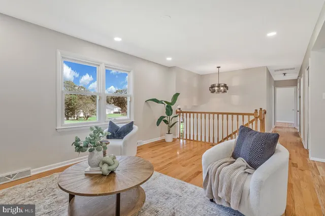 a living room with furniture large window and wooden floor