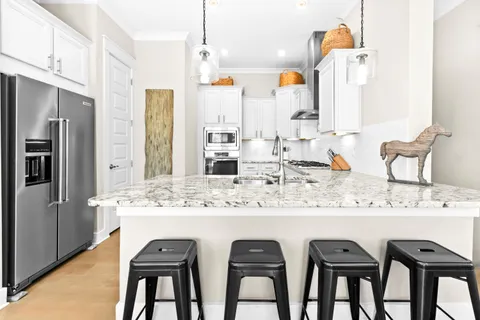 a kitchen with stainless steel appliances granite countertop a sink and chairs