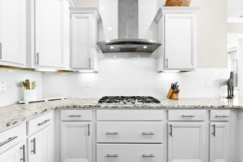 a kitchen with granite countertop white cabinets and a stove