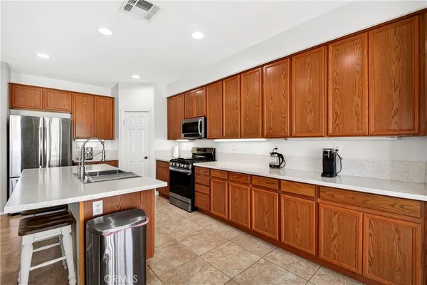 a large kitchen with stainless steel appliances granite countertop a large counter top a stove a sink dishwasher a dining table and chairs with wooden floor