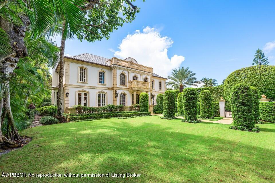 a view of a house with a big yard and potted plants and large trees