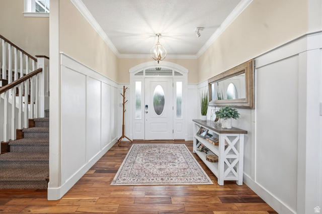 672 Perry Hollow Drive Mapleton, UT 84664 - Photo 18 of 106 Entryway featuring wood-finish flooring, white wainscoting, and an arched front door with sidelights