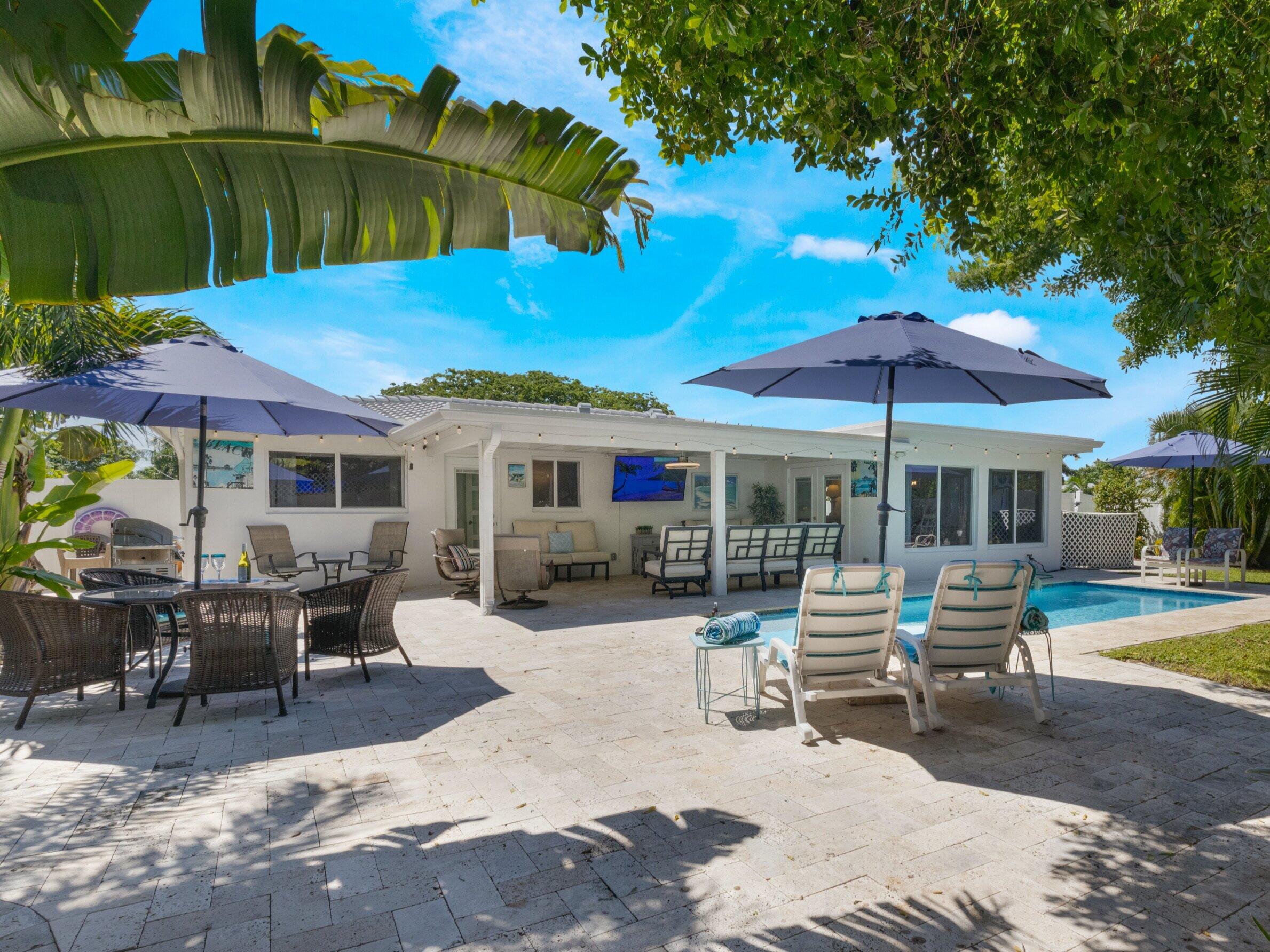 301 Northeast 23rd Street Boca Raton, FL 33431 - Photo 36 of 43 a patio with a table and chairs under an umbrella