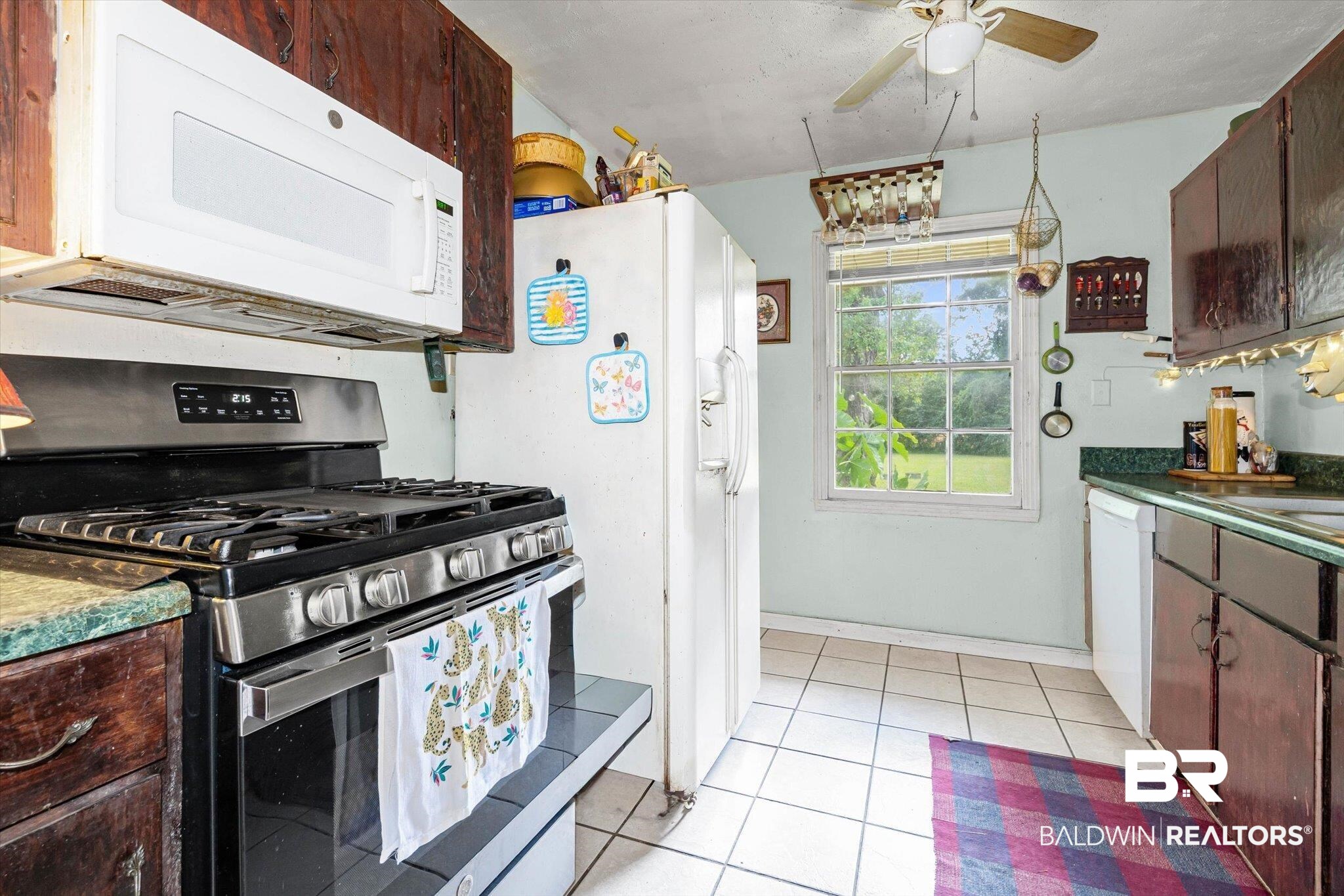 7991 Three Notch Road Theodore, AL 36582 - Photo 6 of 22 Kitchen featuring white appliances, dark countertops, light tile patterned floors, and dark brown cabinets