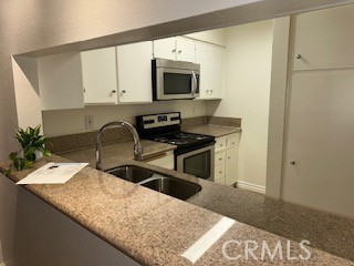 10655 Lemon Avenue, Unit 3401 Rancho Cucamonga, CA 91737 - Photo 8 of 27 a kitchen with granite countertop a sink and a stove top oven with wooden floor