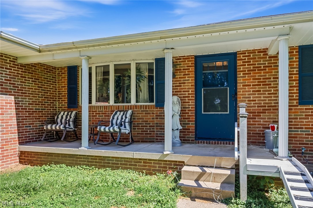 6890 Refugee Road Pickerington, OH 43147 - Photo 6 of 49 Brick facade home featuring a covered front porch, white columns, blue entry door, and dark blue shutters