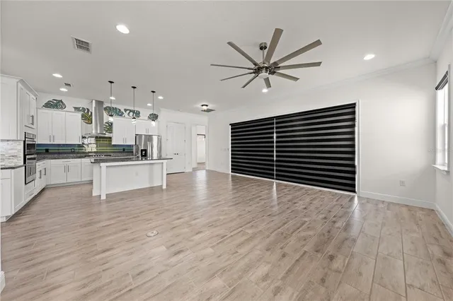 a view of a hallway with wooden floor and cabinets