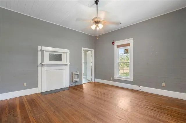 a view of an empty room with a window and wooden floor