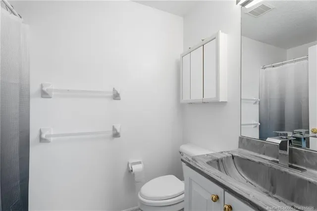 a bathroom with a granite countertop sink toilet and mirror