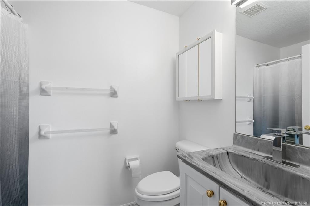 800 Southeast Waterside Way Stuart, FL 34997 - Photo 23 of 27 a bathroom with a granite countertop sink toilet and mirror