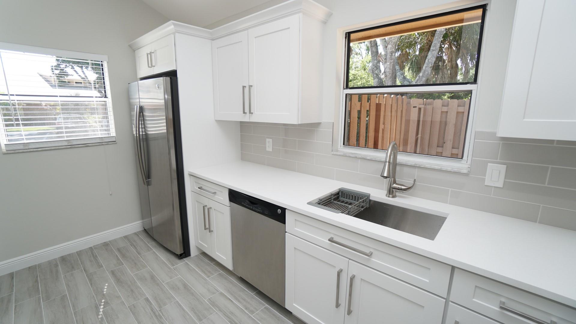 91 Maplecrest Circle Jupiter, FL 33458 - Photo 25 of 27 a kitchen with white cabinets and window