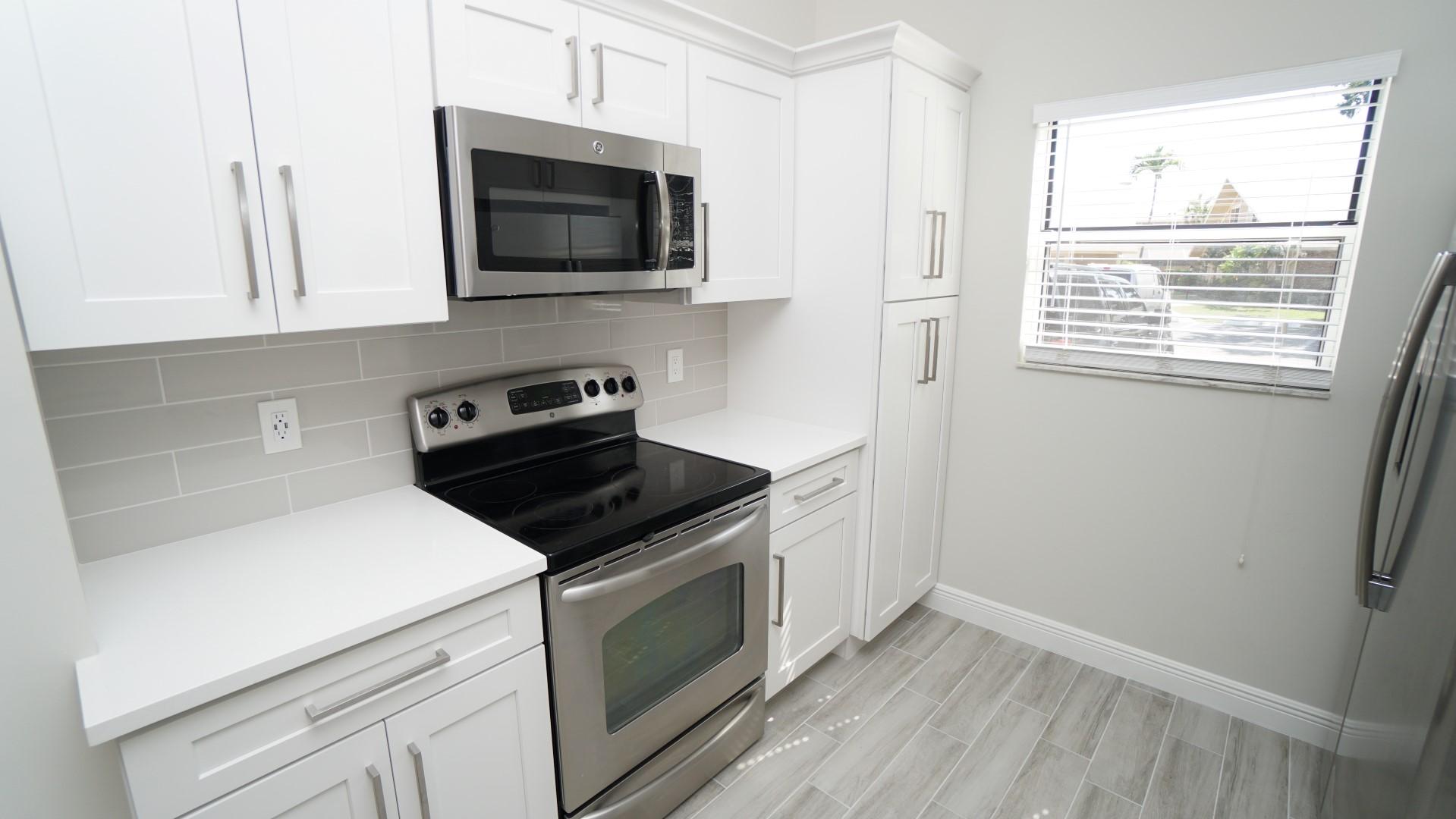 91 Maplecrest Circle Jupiter, FL 33458 - Photo 26 of 27 a kitchen with granite countertop white cabinets and black appliances