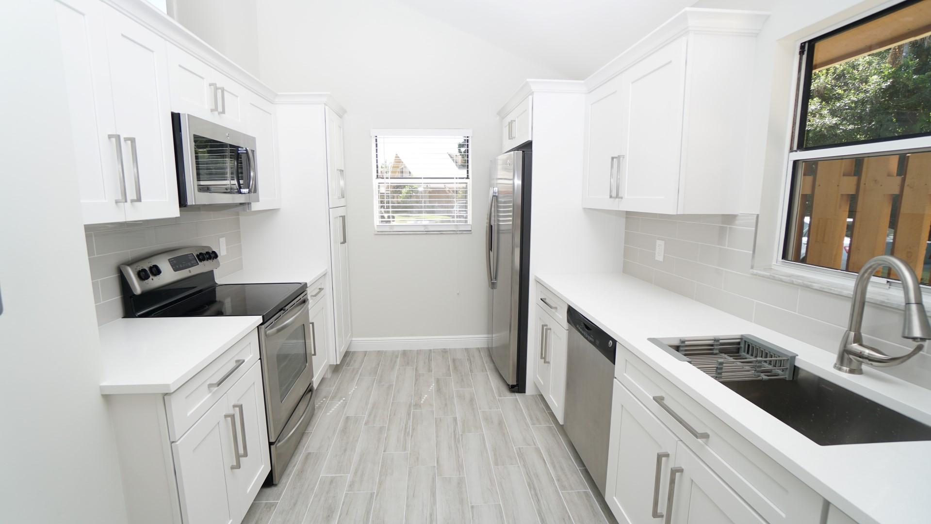 91 Maplecrest Circle Jupiter, FL 33458 - Photo 6 of 27 a kitchen with granite countertop a sink stove and refrigerator