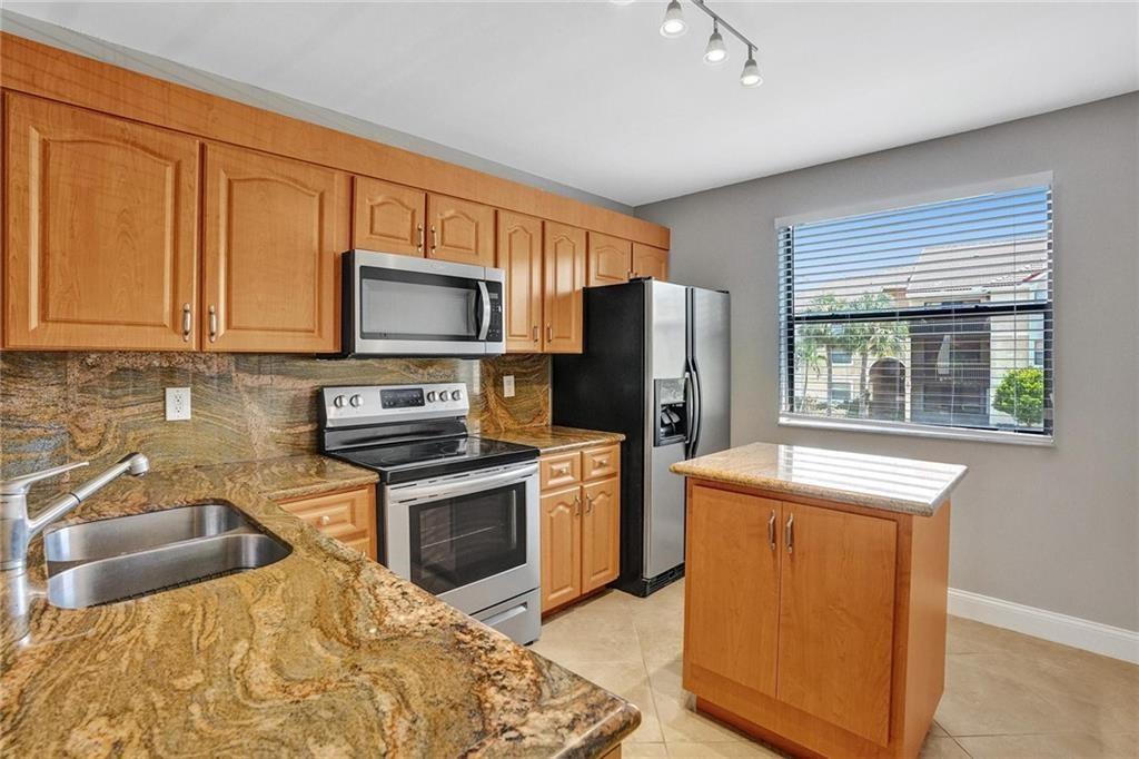 a kitchen with granite countertop a stove a sink and a microwave