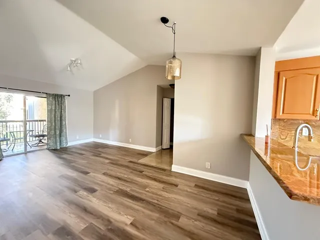a view of an empty room with window and wooden floor