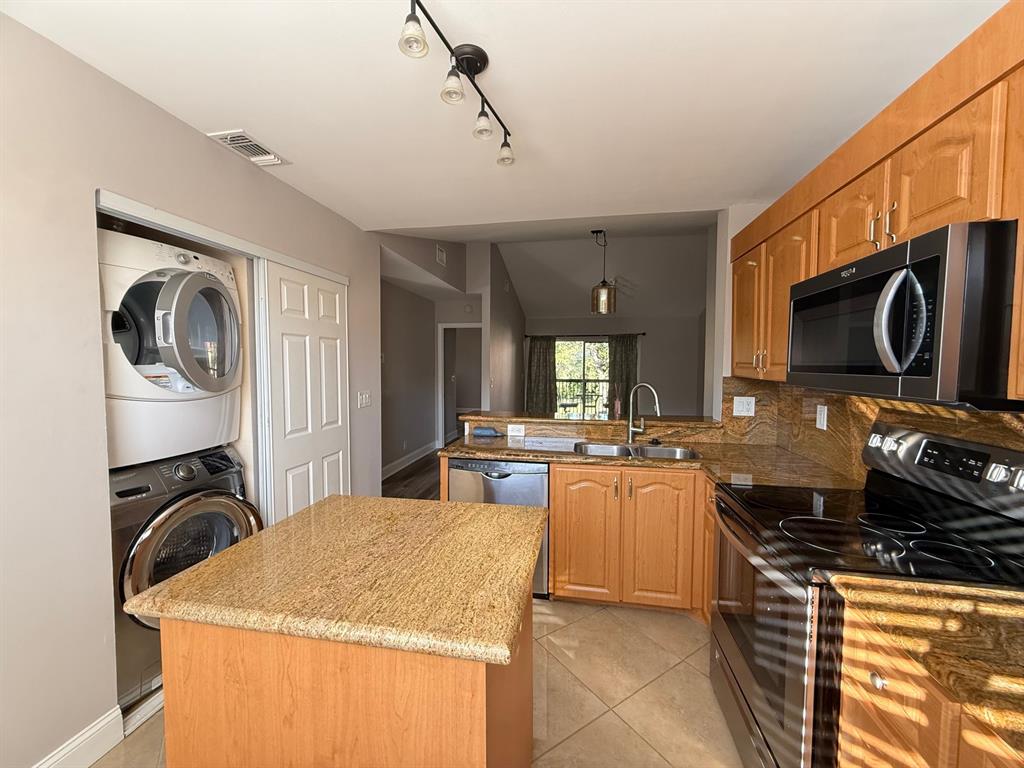 5781 Riverside Drive, Unit 201 Coral Springs, FL 33067 - Photo 14 of 23 a kitchen with kitchen island granite countertop a stove top oven a sink a counter space and cabinets