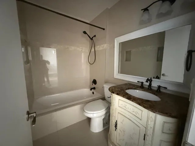 a bathroom with a granite countertop sink toilet and shower