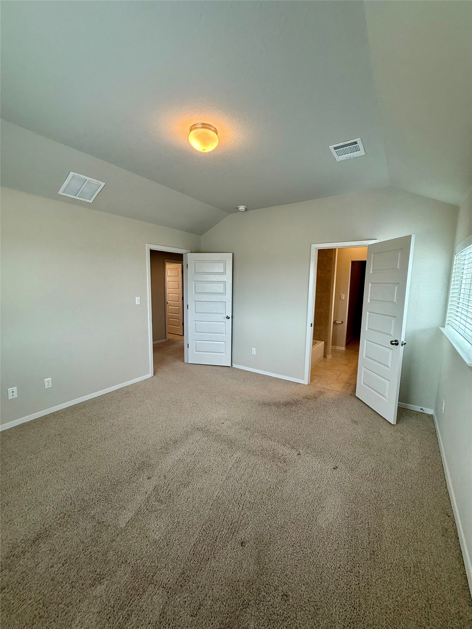 212 Lake Placid Run Elgin, TX 78621 - Photo 14 of 27 A spacious bedroom with vaulted ceilings, plush carpeting, and direct bathroom access.