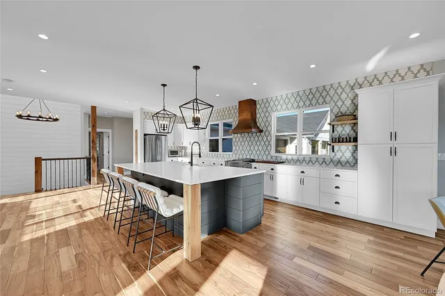 a kitchen with stainless steel appliances kitchen island granite countertop a table chairs in it and wooden floors