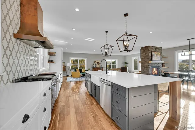 a view of a kitchen with kitchen island a stove a sink a chimney and a center island