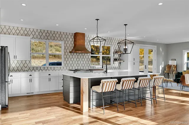 a kitchen with stainless steel appliances kitchen island granite countertop a table chairs and a wooden floor