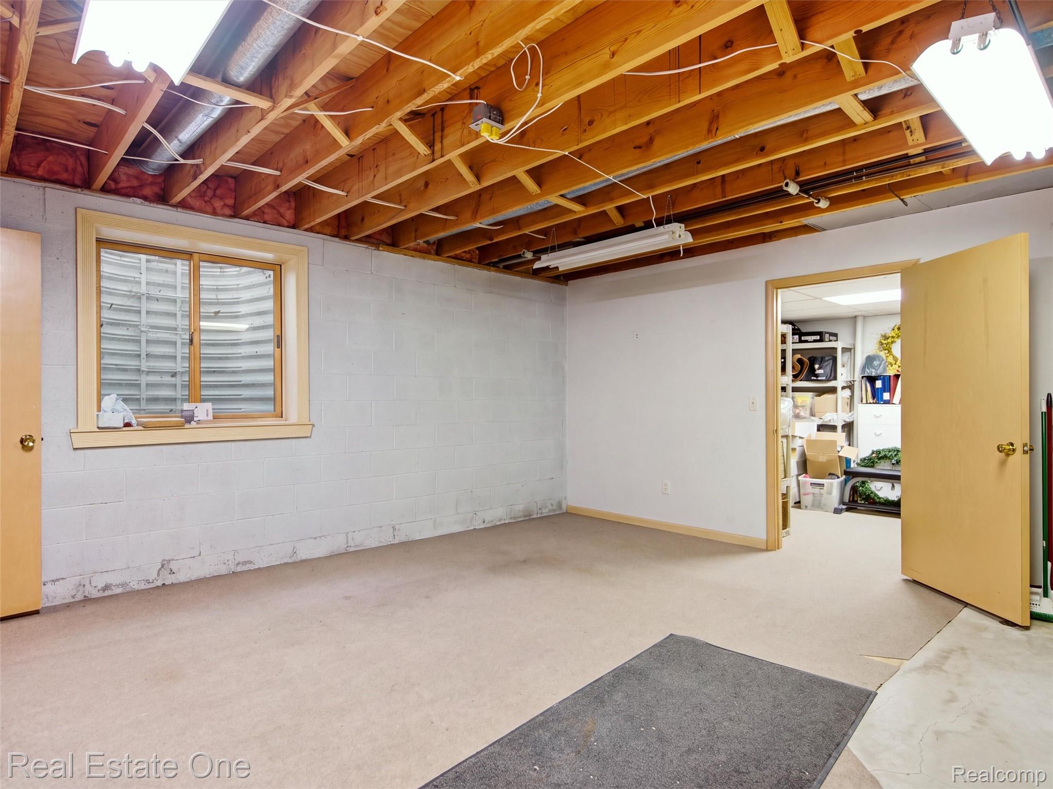2626 West Wattles Road Troy, MI 48098 - Photo 33 of 65 Unfinished basement space with exposed wood joists, concrete block walls, and a window well providing natural light