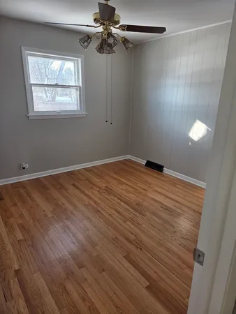 an empty room with windows and fan