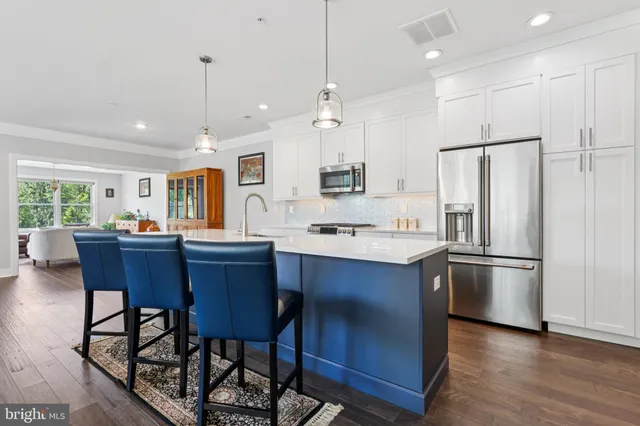 a kitchen with stainless steel appliances granite countertop a refrigerator a stove a sink a dining table and chairs with wooden floor