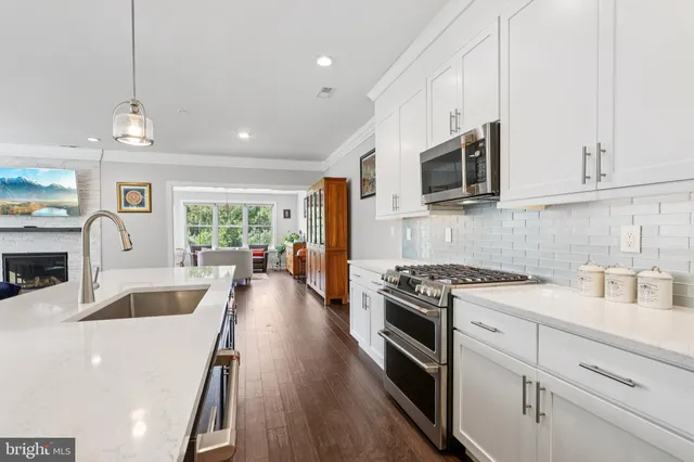 a kitchen with stainless steel appliances granite countertop a stove a sink a refrigerator a stove and white cabinets with wooden floor