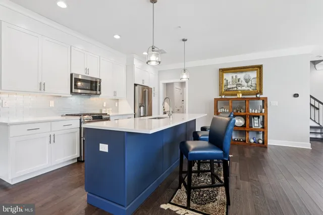 a kitchen with stainless steel appliances granite countertop a stove a sink dishwasher a dining table and chairs with wooden floor