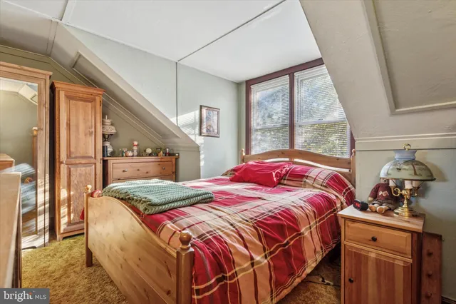 a bedroom with a bed and a dresser next to a window