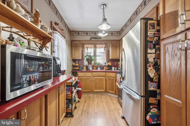 a kitchen with stainless steel appliances granite countertop a refrigerator and a wooden floor