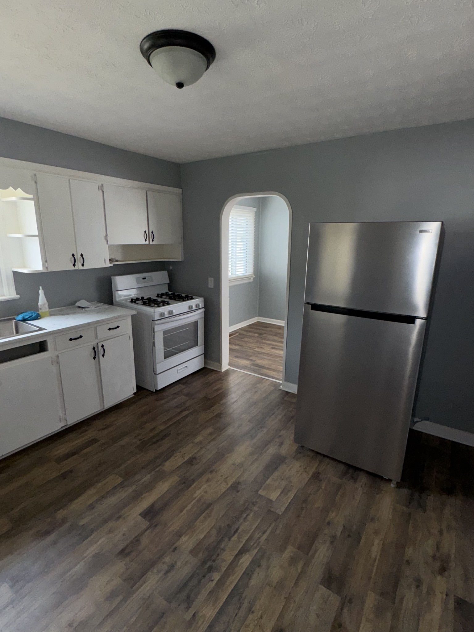 402 East Locust Street Princeton, KY 42445 - Photo 29 of 32 a kitchen with stainless steel appliances granite countertop a refrigerator a sink a stove and white cabinets with wooden floor