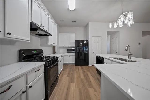 a kitchen with stainless steel appliances a sink dishwasher a stove top oven a refrigerator with island and cabinets