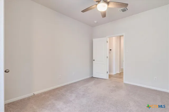 an empty room with a ceiling fan and a window