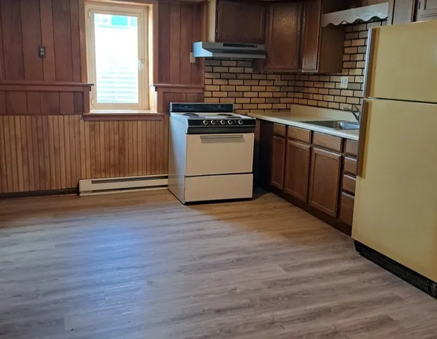 a kitchen with granite countertop wooden floors and white stainless steel appliances