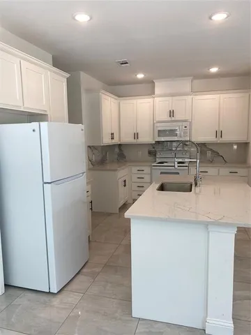 a kitchen with a refrigerator a sink and white cabinets