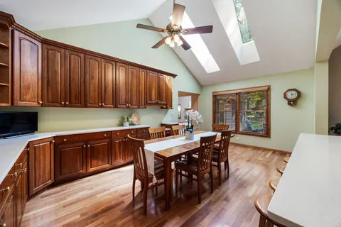 a kitchen with stainless steel appliances granite countertop a dining table chairs and a refrigerator