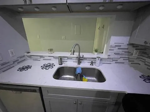 a kitchen with a sink and a stove with wooden floor